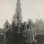 Grupa kobiet z chłopcem stoi na schodach w Częstochowie. Z tyłu Jasna Góra.