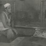 Fotografia przedstawiająca piekarza przy piecu w piekarni.