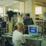 Fotografia przedstawia bibliotekarkę przy komputerze obsługującą czytelnika.