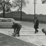 Fotografia przedstawia grupę osób na stanowiskach parkingowych, które z pomocą wiader z farbą i pędzli malują pasy.