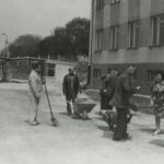 Fotografia przedstawia grupę osób z łopatami i taczkami.