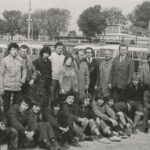 Fotografia przedstawia grupę mężczyzn, kobiet, młodzieży pozujących wspólnie do zdjęcia na tle autobusów.