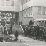 Fotografia przedstawia grupę ludzi stojących przy pierwszej posadzonej tui.