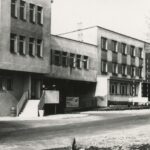 Fotografia przedstawia widok budynku, przy którym stoi tablica: "Bez znajomości przepisów BHP wstęp zajezdni zabroniony".