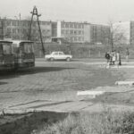 Fotografia przedstawia odgrodzony plac, na którym stoją autobusy. Z tyłu widoczne bloki.