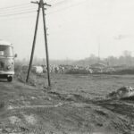 Fotografia przedstawia widok na plac, gdzie składuje się materiały budowlane. Widoczny słup oraz autobus.