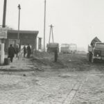 Fotografia przedstawia fragment budynku z napisem "Chrzanów". Po prawej widoczna rozkopana nawierzchnia oraz ciężarówki i autobus.