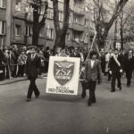 Fotografia przedstawia ludzi niosących tablicę „Fablok. ZSZ Chrzanów. Szkoła Przyzakładowa”. Z tyłu kolejne osoby ze sztandarami.