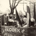 Fotografia przedstawia opiekunki i pielęgniarki z dziećmi jadące na skrzyni fablokowskiego samochodu. Z boku napis „Żłobek zakładowy Fablok”.
