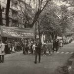 Fotografia przedstawia pochód pierwszomajowy. Na pierwszym planie widoczny transparent z hasłem „Granica na Odrze i Nysie – granicą pokoju”.