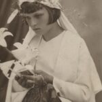 Fotografia przedstawia młodą dziewczynę w białym ubraniu. W rękach trzyma różaniec, obrazek oraz lilie.