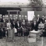 Fotografia przedstawia grupę kobiet i mężczyzn oraz ekspozycję sprzętu pszczelarskiego.