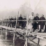 Fotografia przedstawia żołnierzy idących przez drewniany most.