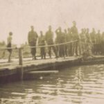 Fotografia przedstawia żołnierzy idących przez drewniany most.